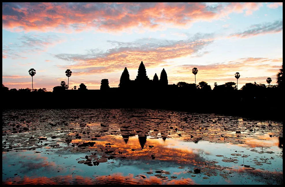 Gün doğumunda Angkor Wat'ın silueti ve su yansıması.