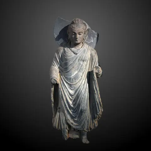 Ayakta bir Buda heykeli (Commons dosya adındaki “MA 6284” bir envanter numarasına benzer; kayıt eserin yerini ve tarihini belirtmez, fotoğraf 25 Haziran 2017 tarihlidir). Wikipedia'ya göre ilk insan biçimli Buda heykelleri 1.–2. yüzyıllarda Gandhara'da ortaya çıktı; yani bu tür heykeller Buda'nın yaşadığı dönemden yüzyıllar sonrasına aittir.