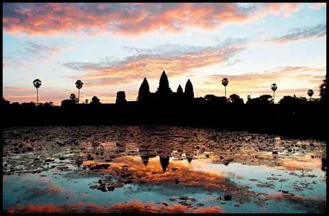 Gün doğumunda Angkor Wat'ın silueti ve su yansıması.